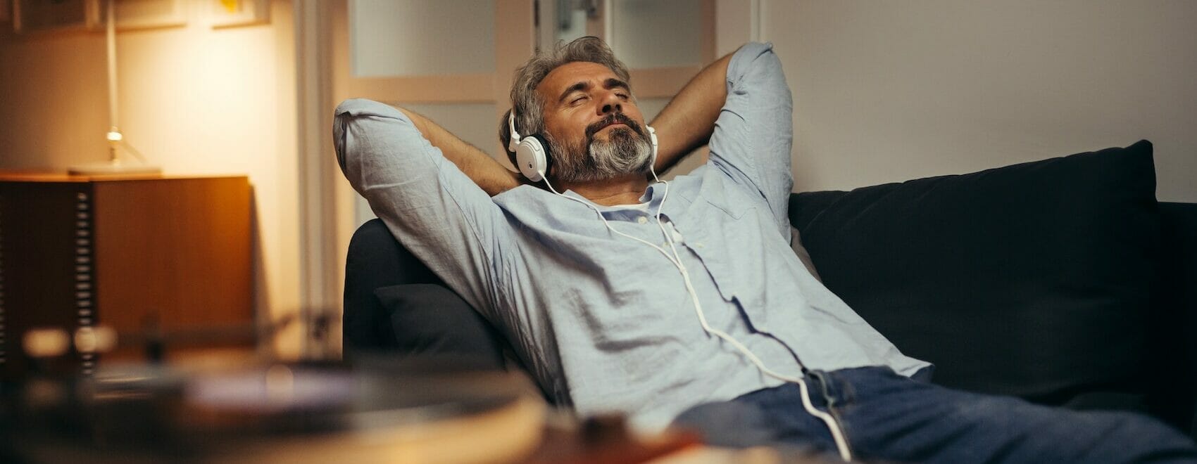 man listening music with headphones relaxed in sofa