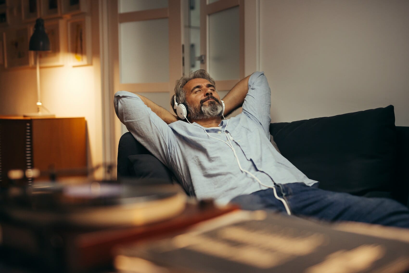 man listening music with headphones relaxed in sofa